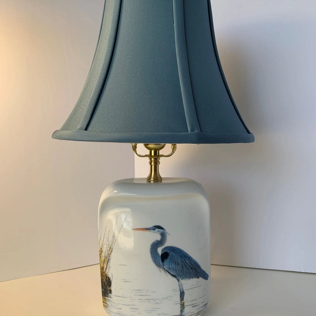 A lamp with a bird on it sitting on top of a table.