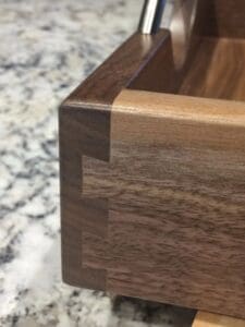 Close-up of a wooden box corner displaying dovetail joints against an Abstract Floral Tiled Tray on Walnut.